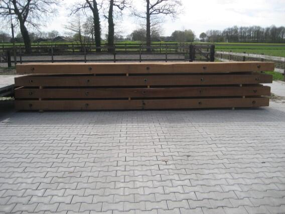Lange stapel Basralocus draglineschotten op klinkers voor een hek met weiland