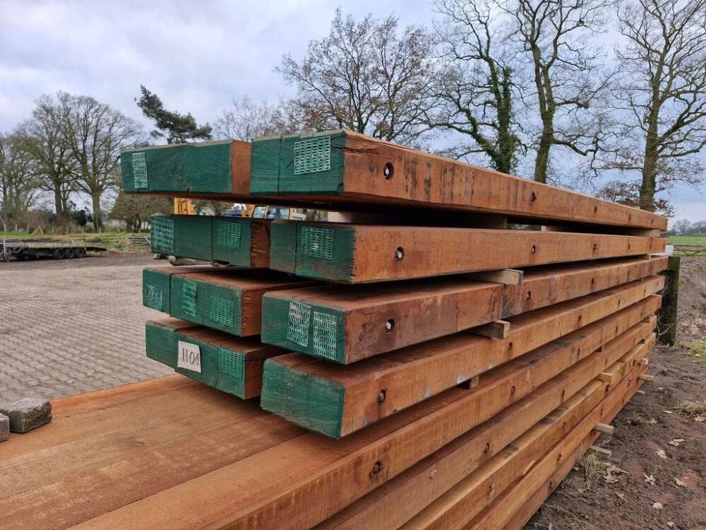 Close-up van gestapelde nieuwe draglineschotten met groene kopse kanten op zandgrond