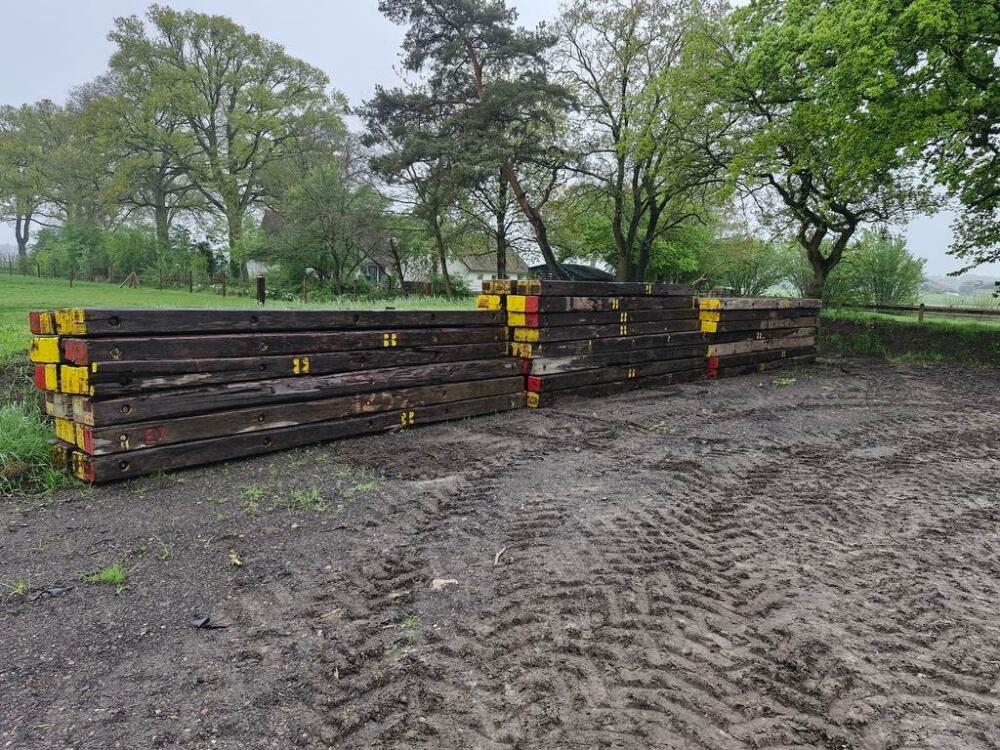 Gebruikte donkere draglineschotten met gele labels gestapeld op een modderige bouwplaats