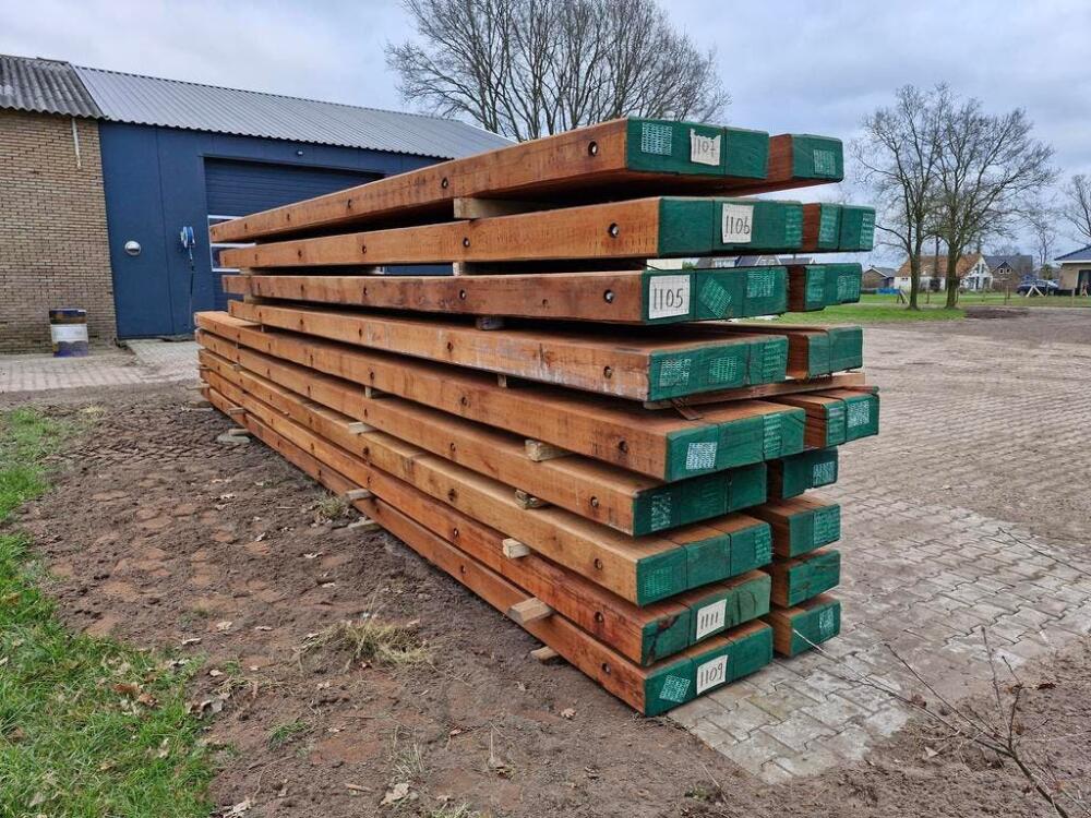 Gestapelde nieuwe draglineschotten met groene uiteinden en bouten onder een overkapping